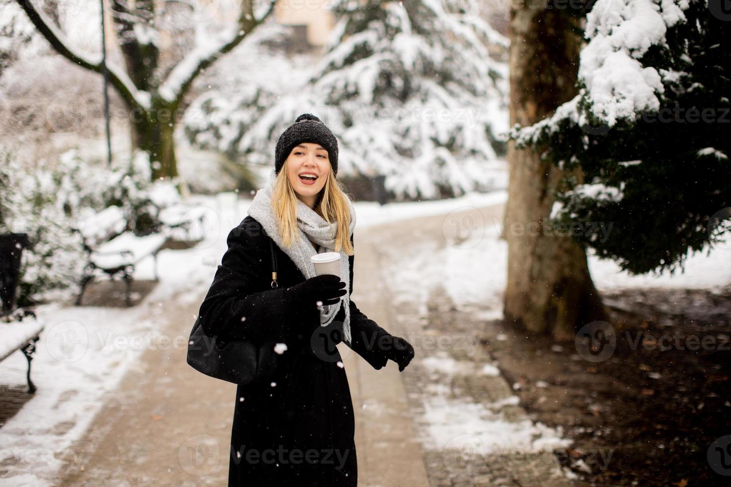 giovane donna con caldo Abiti nel freddo inverno neve potabile caffè per partire foto