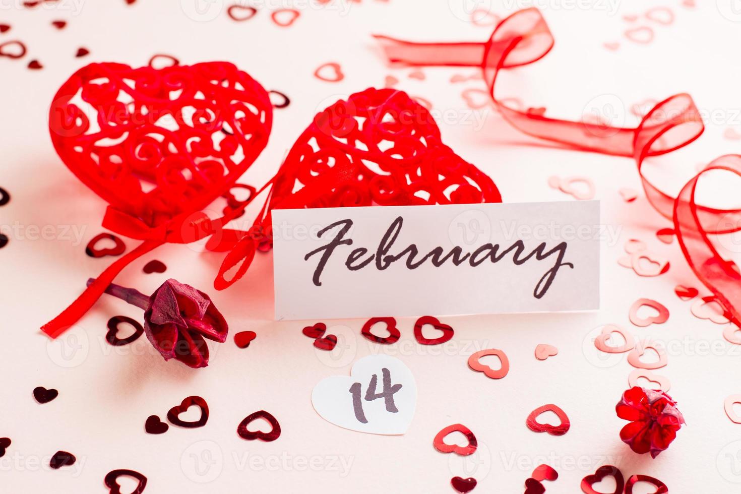 San Valentino giorno. Data di febbraio 14, asciutto fiore e rosso Riccio cuori su un' rosa sfondo disseminato con cuori foto