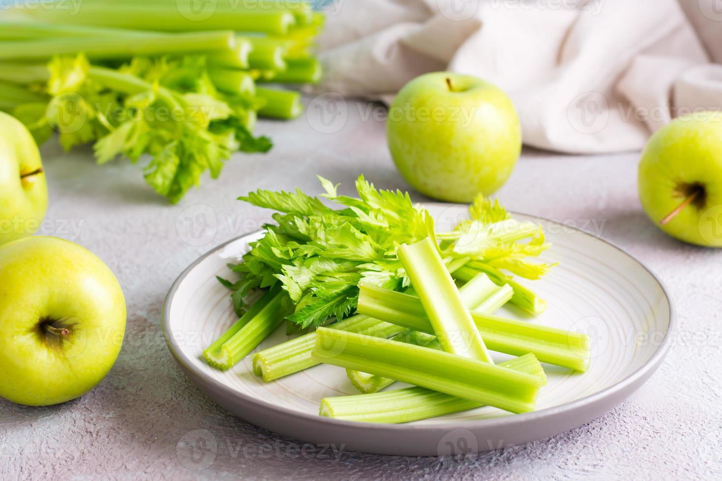 affettato fresco sedano gambo con le foglie su un' piatto e verde mele su il tavolo pronto per essere cucinato. vegetariano cibo foto