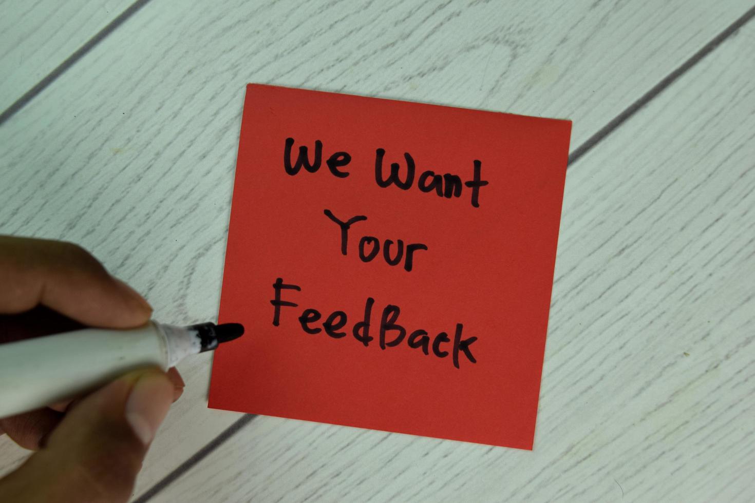 vogliamo il tuo feedback scritto sul blocco note isolato sul tavolo di legno foto