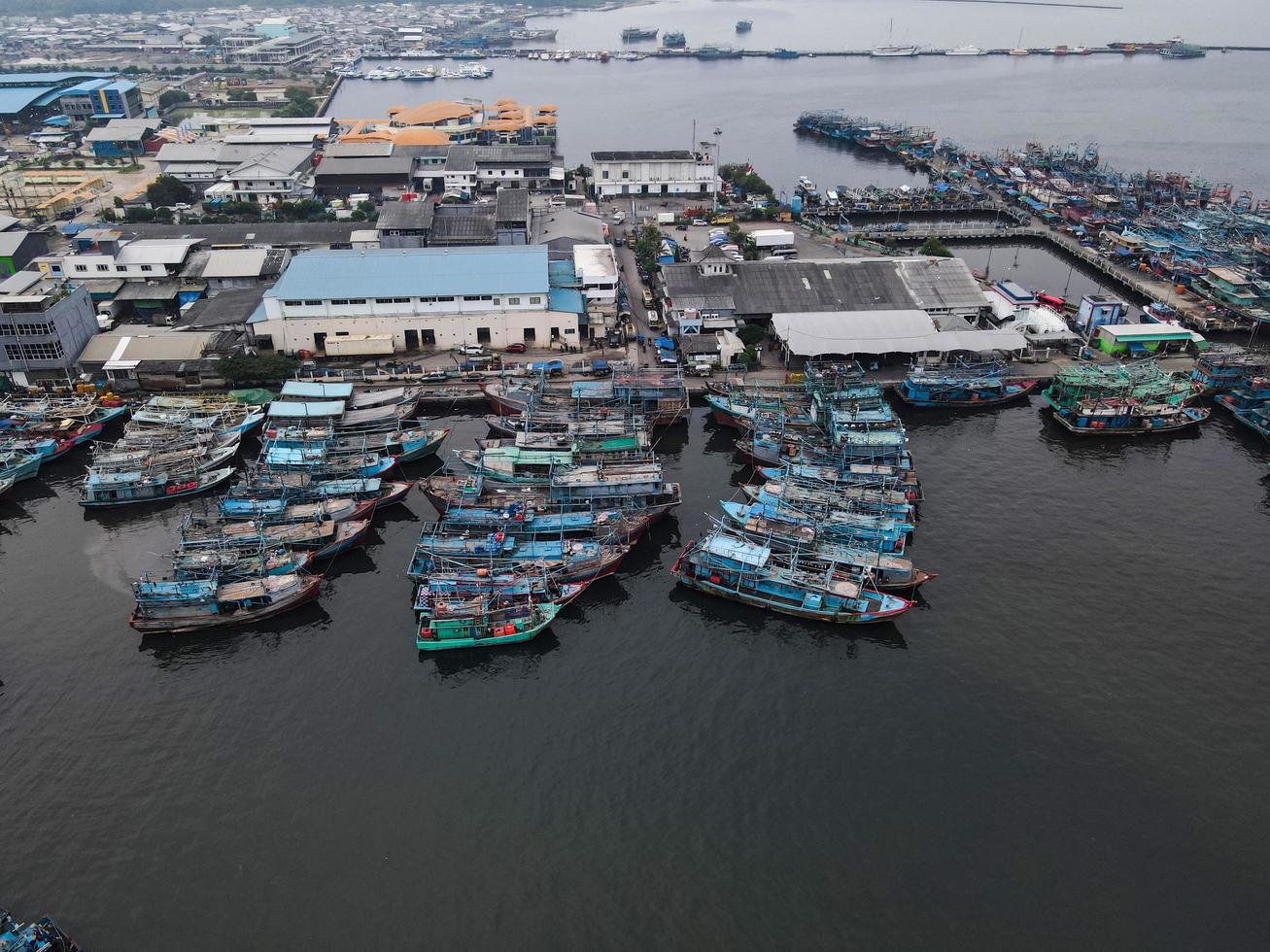 jakarta, indonesia 2021- veduta aerea con drone della spiaggia di muara angke con barche di legno appoggiate al molo foto