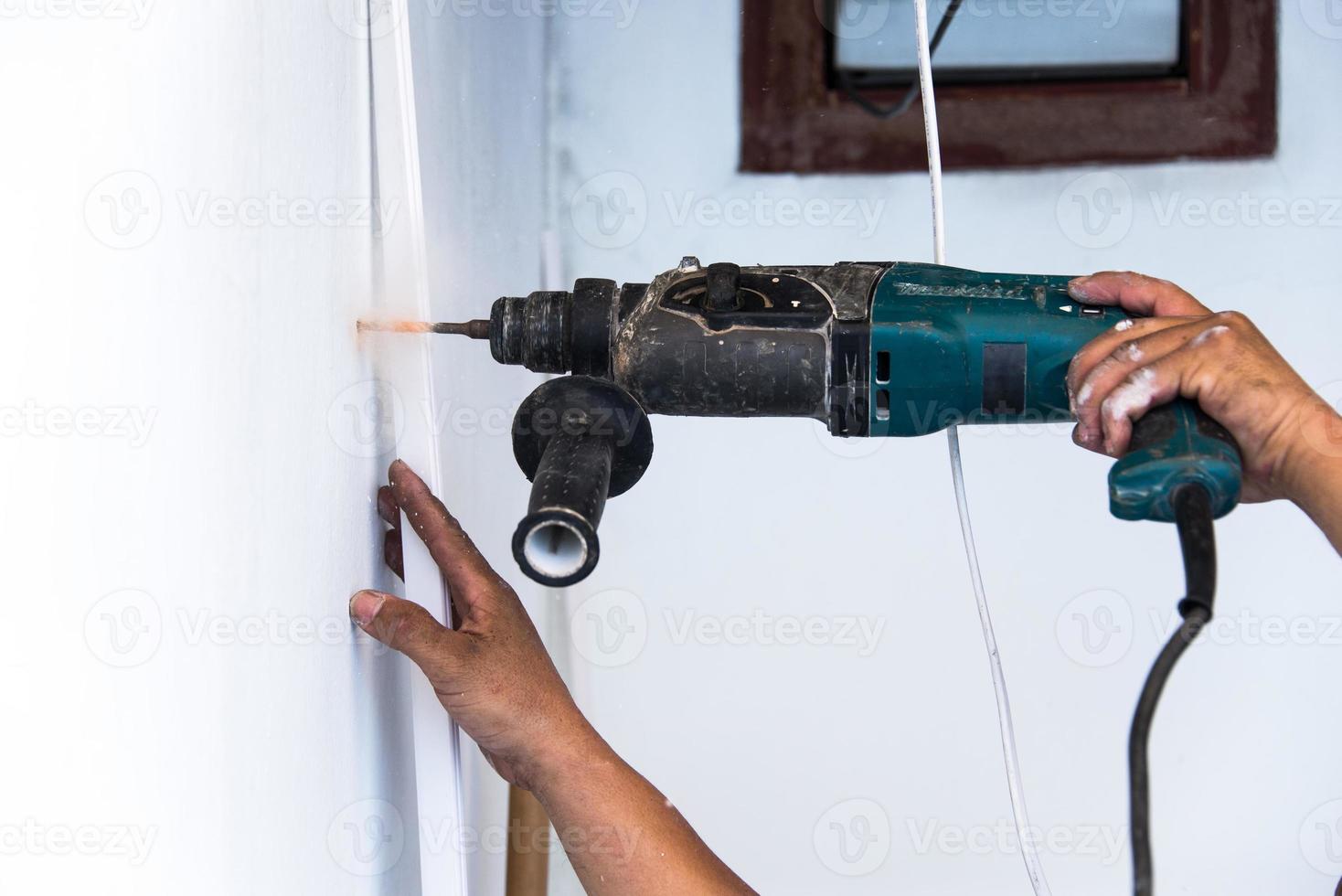 vicino su di elettrico trapano fabbricazione buco nel un' parete, riparazione, edificio e casa concetto foto