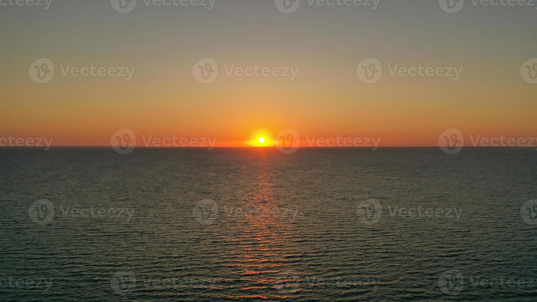 sole che tramonta dietro la linea dell'orizzonte foto