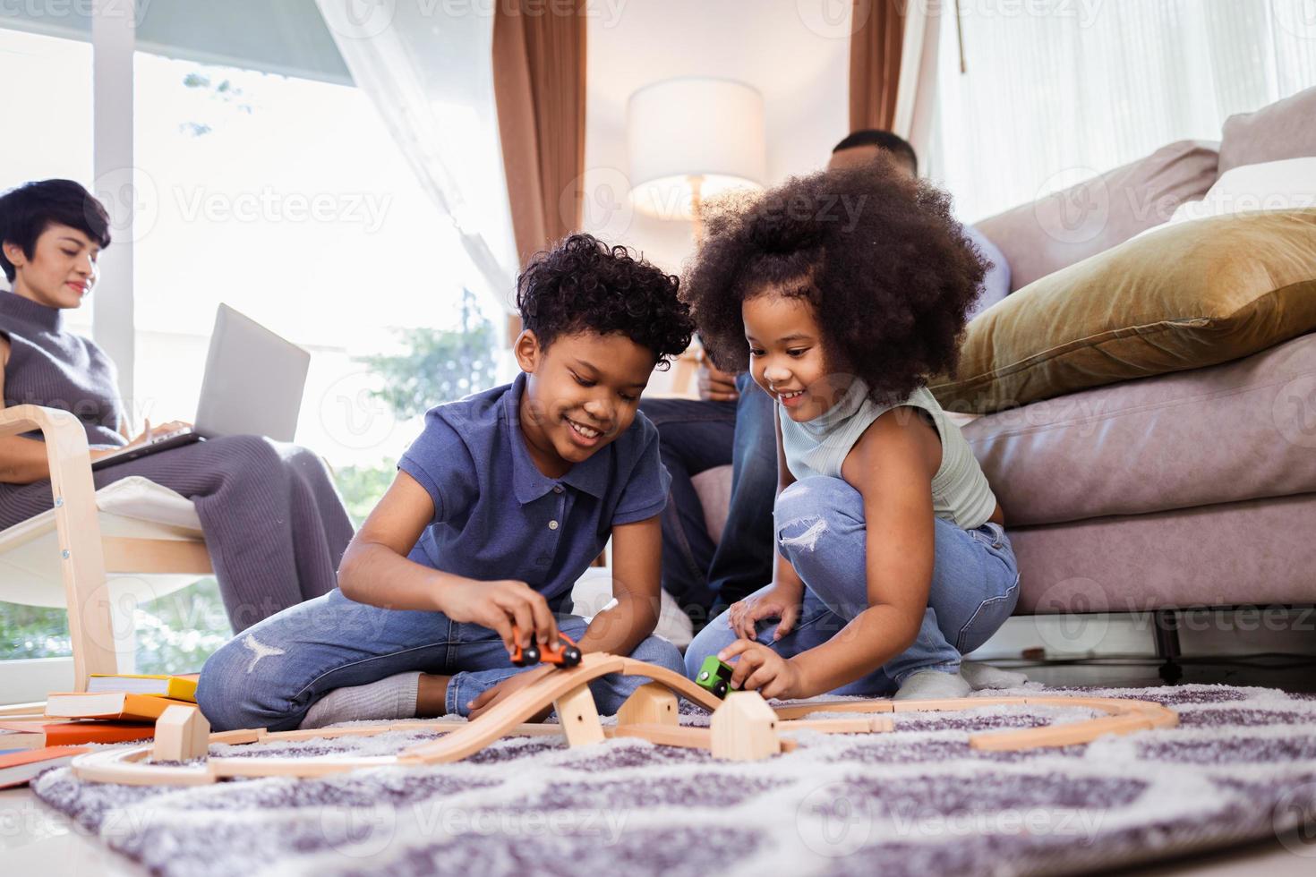 contento America Africa famiglia, figlio e figlia giocare giocattolo nel vivente camera con genitori foto