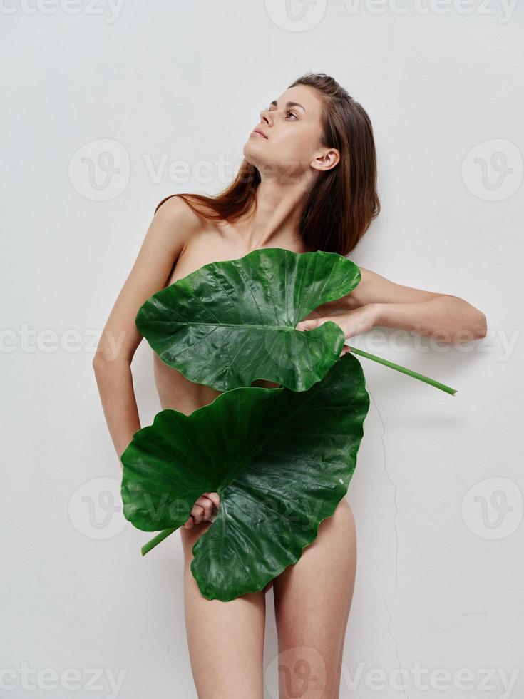 donna con nudo corpo nascondiglio dietro a le foglie esotico fascino leggero sfondo foto