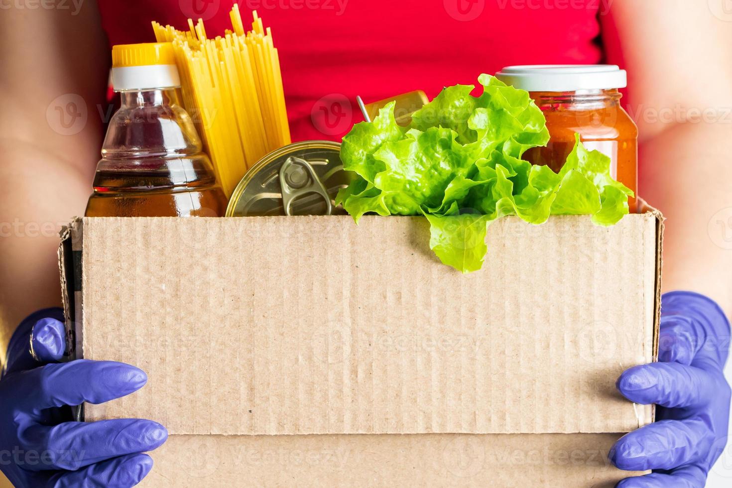 persona in possesso di una scatola di generi alimentari foto