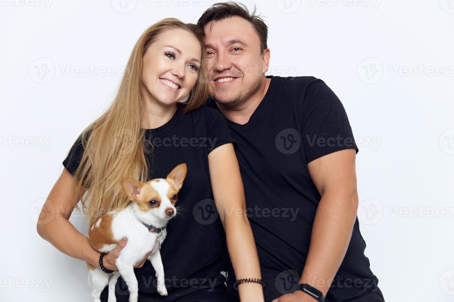 allegro sposato coppia nel nero magliette con un' piccolo cane nel loro mani famiglia foto