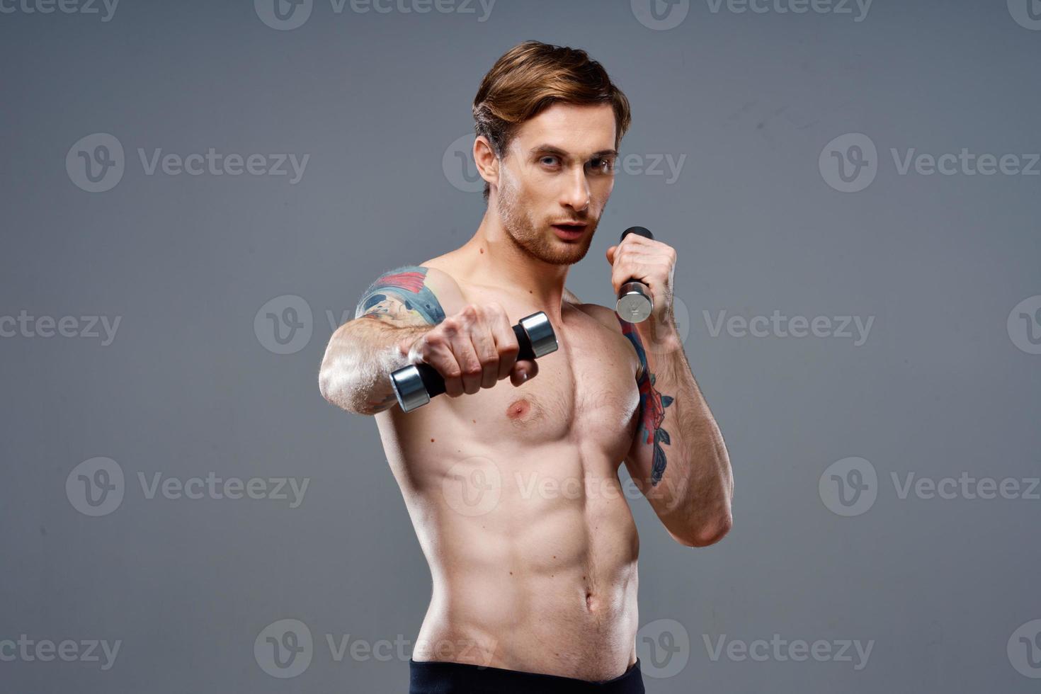 nudo atleta con un' tatuaggio e manubri nel mani Telefono fitness bodybuilding foto