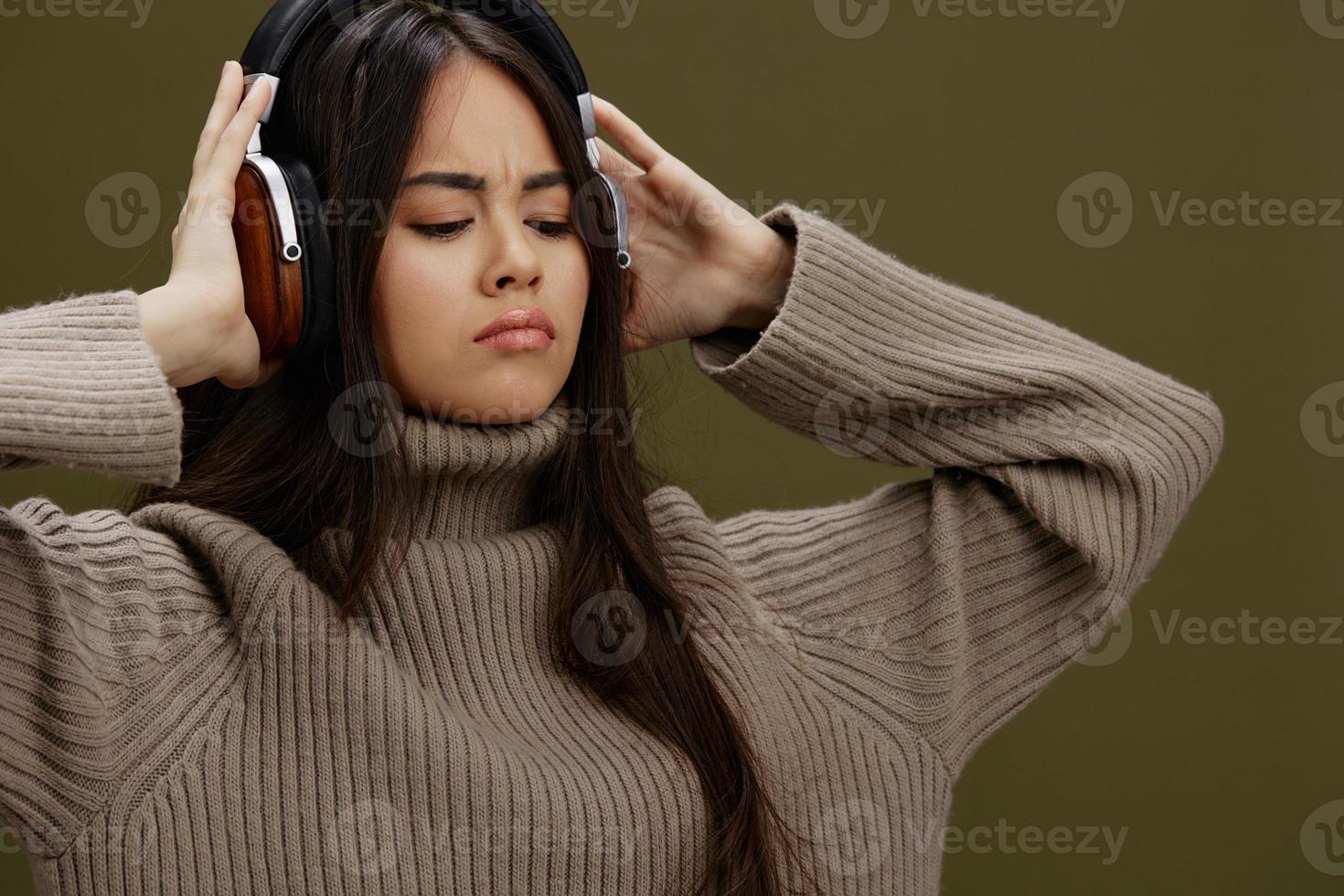 bellissimo donna nel un' maglione ascoltando per musica con cuffie divertimento stile di vita foto