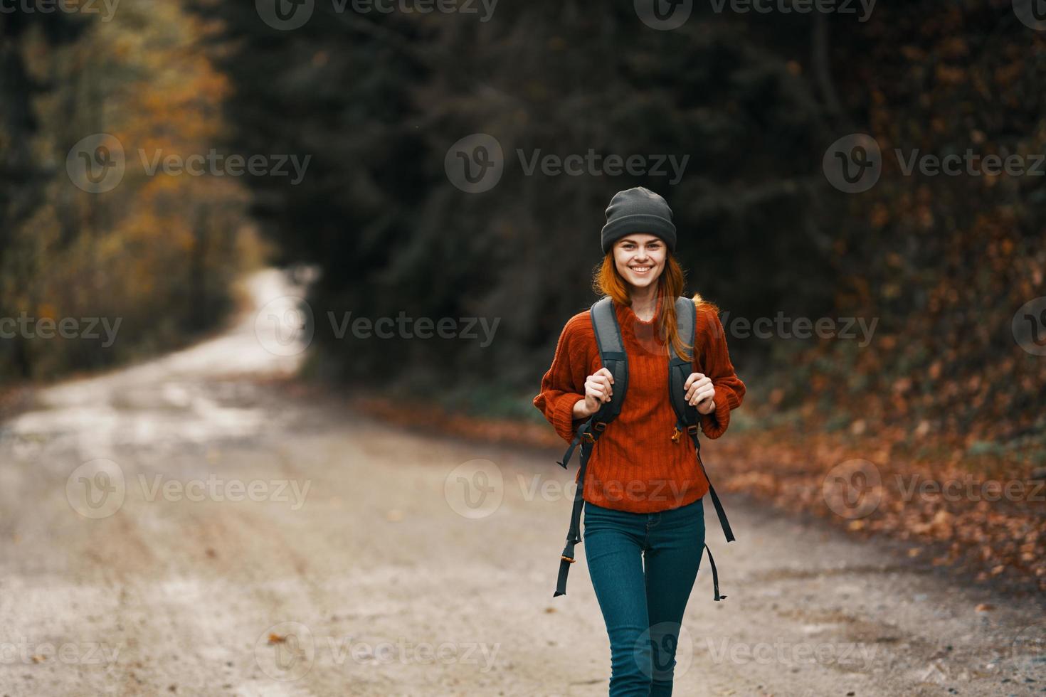 donna con un' zaino nel pieno crescita passeggiate lungo il strada nel il foresta nel autunno foto