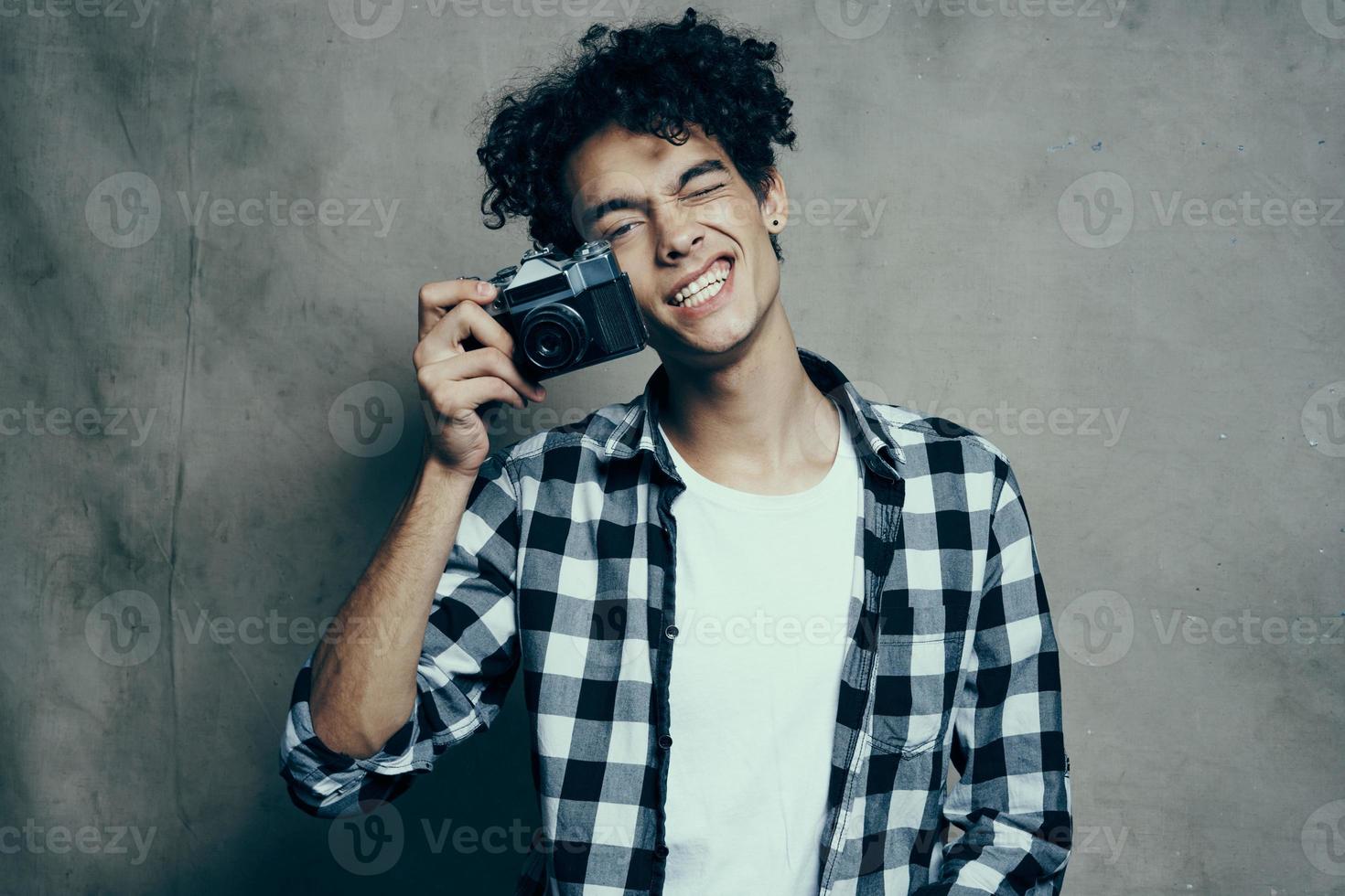 fotografo nel un' plaid camicia con un' telecamera nel il suo mano su un' grigio sfondo nel un' passatempo studio camera foto