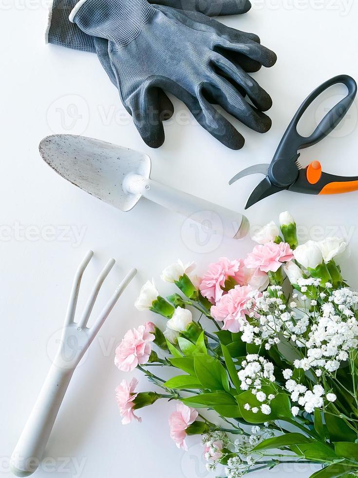 spray rosa e bianca fiori con giardinaggio utensili foto