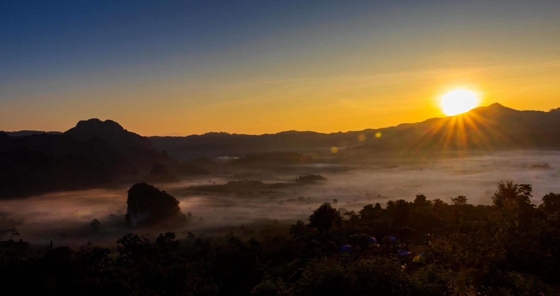 il sole sorge sulle montagne e sulla nebbia foto