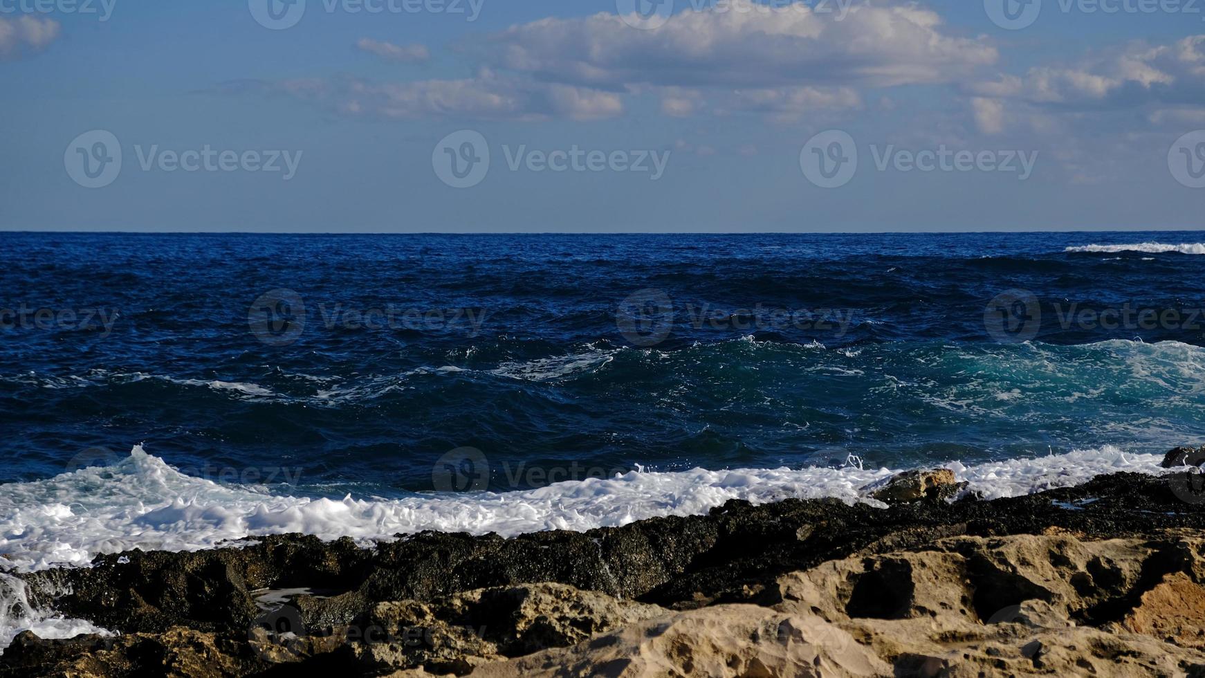 blu mare onda e bianca schiuma e spruzzata. pietra spiaggia su isola di Malta, no sabbioso spiaggia. estate vacanza confine telaio concetto. tropicale isola vacanza sfondo. turista viaggio bandiera design modello. foto
