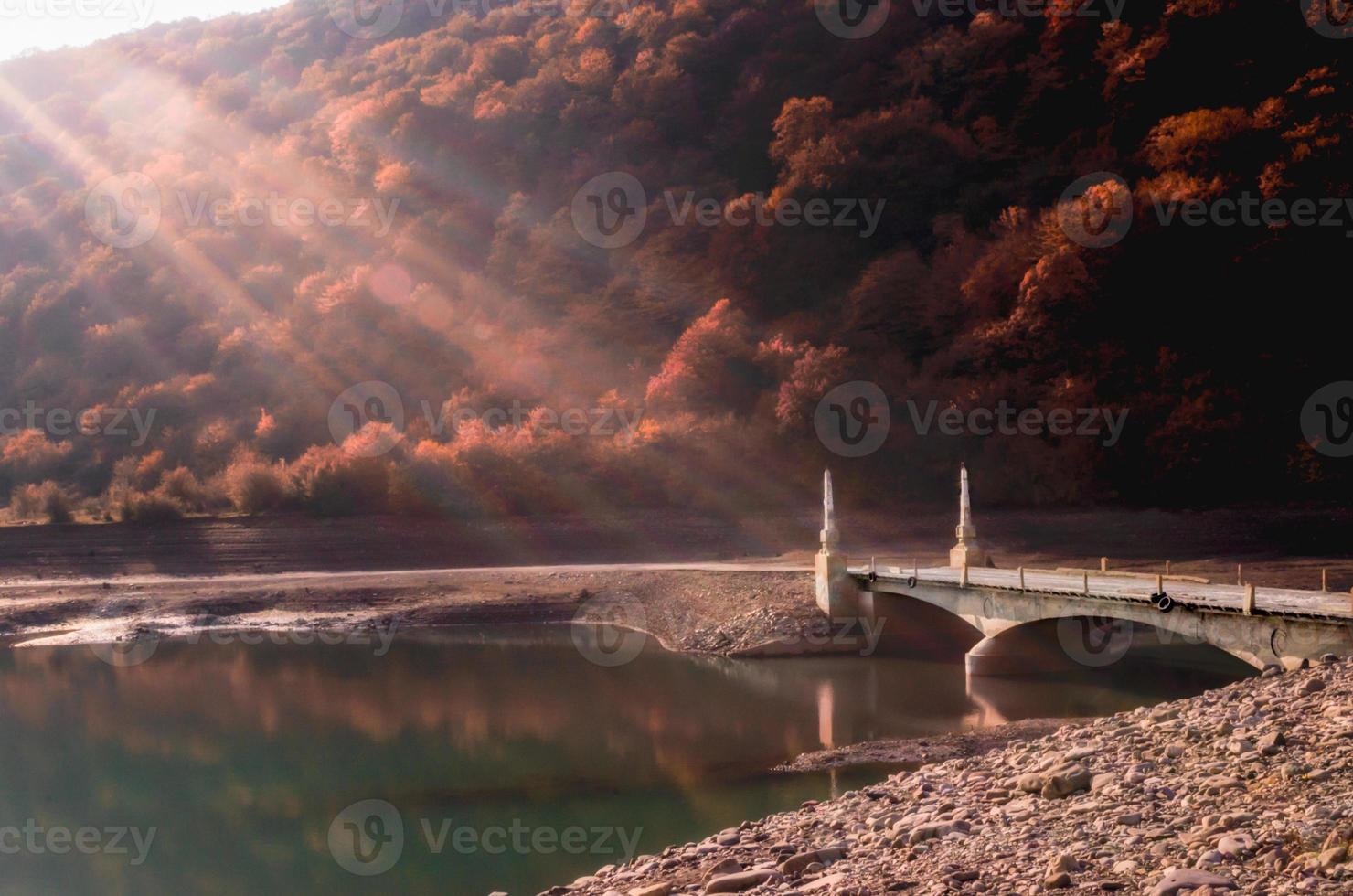 luce del sole su un ponte di pietra su un fiume foto