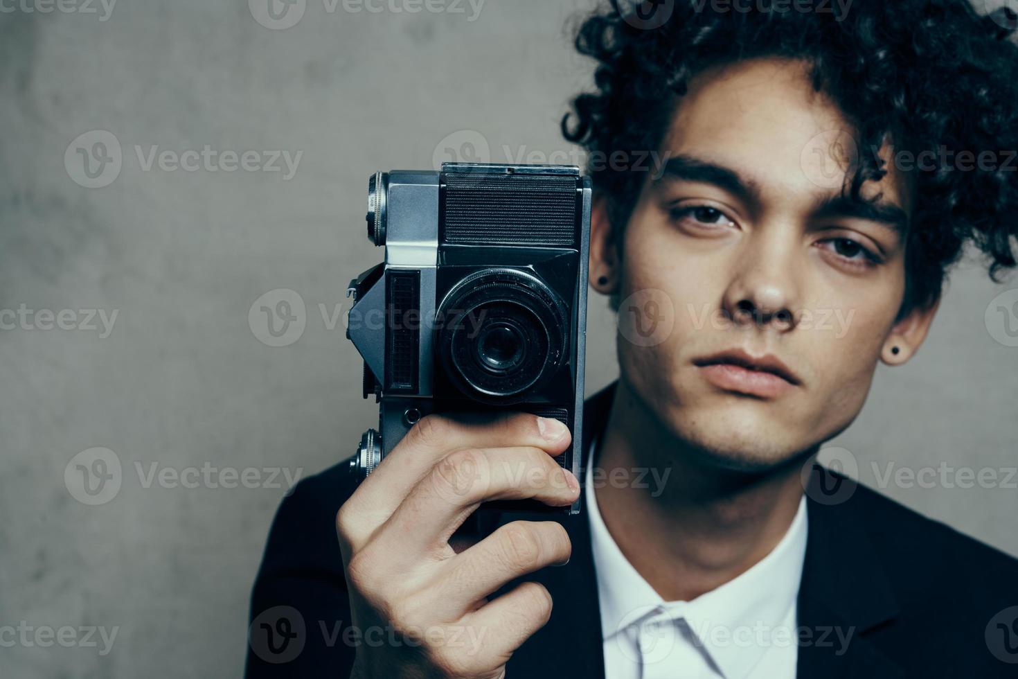 elegante uomo con telecamera nel mano fotografia studio riccioli modello ritratto foto