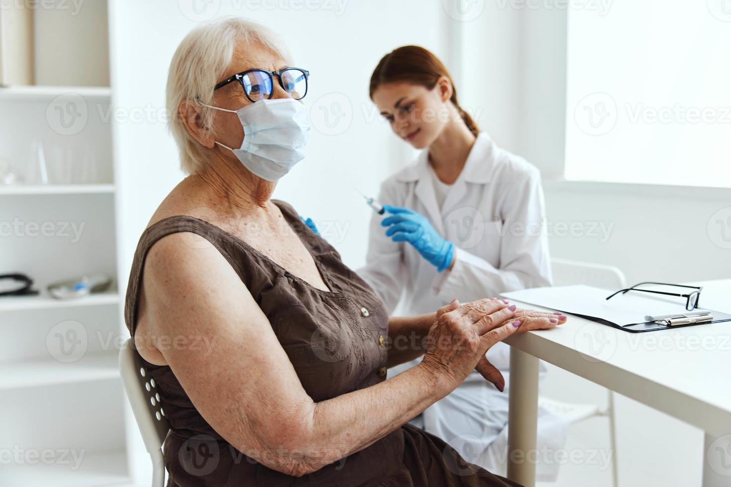 anziano donna indossare un' medico maschera siringa iniezione vaccino passaporto Salute cura foto