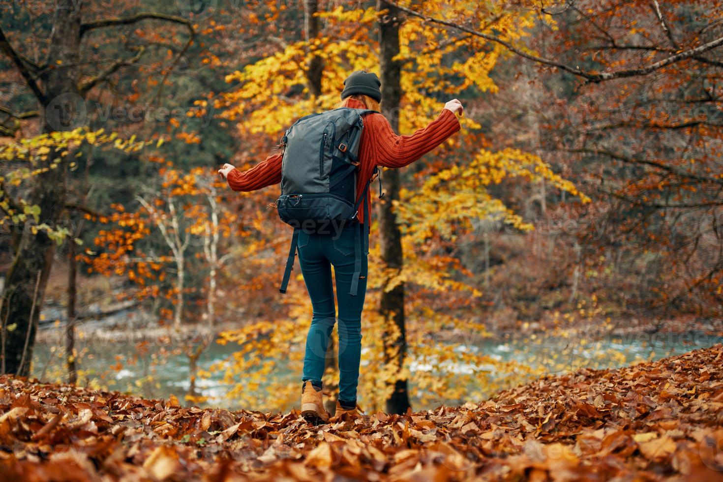 donna nel un' maglione e jeans e stivali nel autunno nel un' parco nel natura vicino il fiume foto