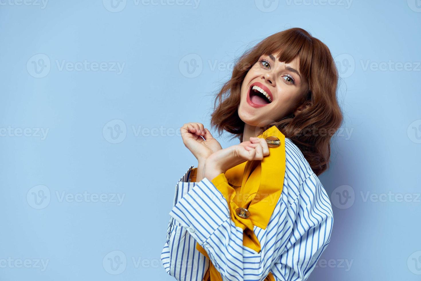 donna nel giallo cappotto con pelliccia largo Aperto bocca Esprimere a gesti con mani blu sfondo foto