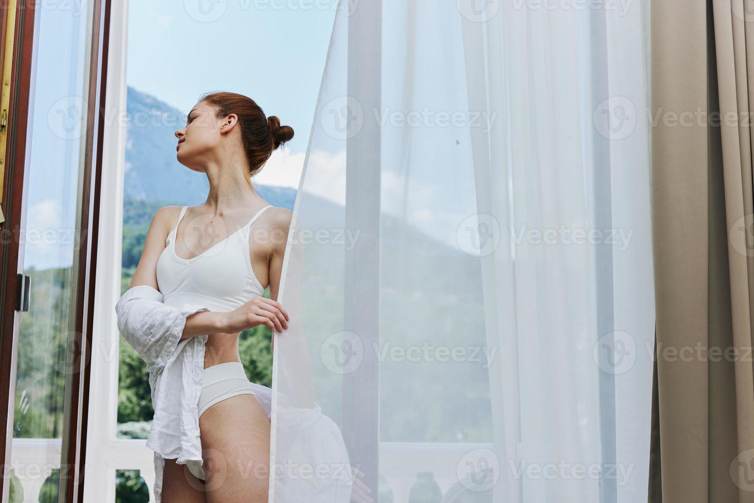 ritratto di un' bellissimo donna sta su un' balcone terrazza nel biancheria intima luce del sole bellissimo Visualizza inalterato foto