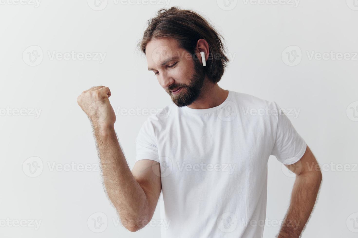 elegante uomo nel un' bianca maglietta con senza fili cuffie nel il suo orecchie avendo divertimento ascoltando per musica Sorridi su un' bianca sfondo stile di vita foto