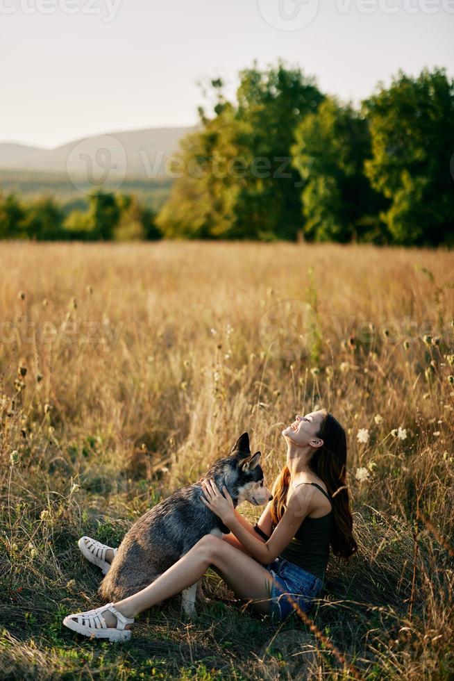 donna seduta nel campo con bassotto cane sorridente mentre la spesa tempo nel natura con amico cane nel autunno a tramonto mentre in viaggio foto