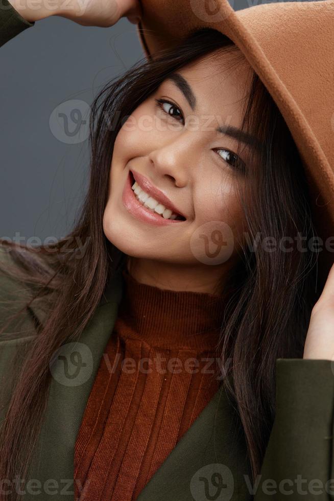 bella donna nel un' completo da uomo con un' cappello in posa casuale indossare grigio sfondo foto