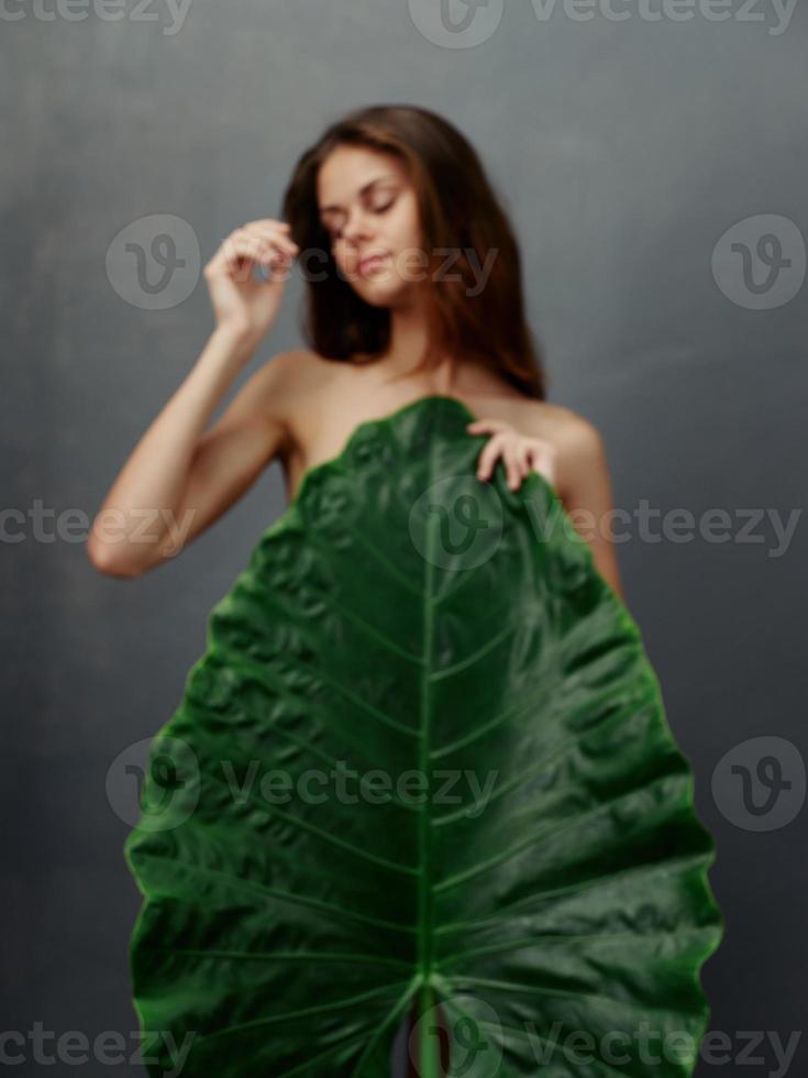 bella donna con grande verde foglia coperture nudo corpo buio sfondo foto