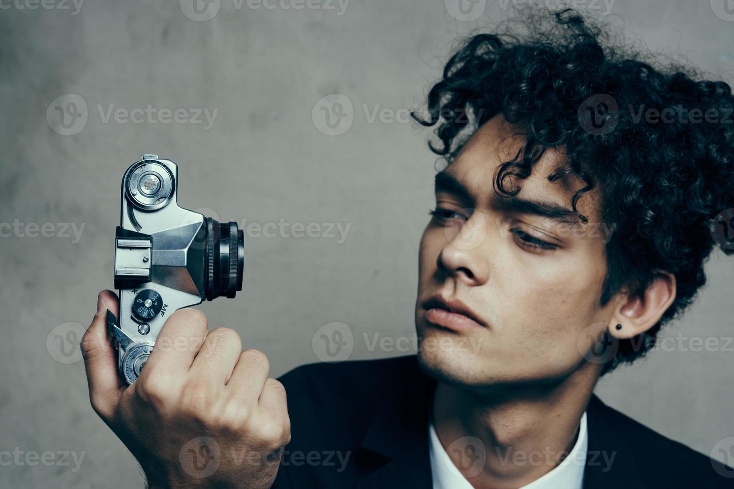 elegante uomo con telecamera nel mano fotografia studio riccioli modello ritratto foto