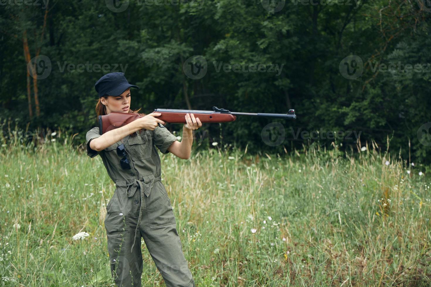 donna soldato nel un' verde tuta da lavoro con un' pistola prende scopo Armi foto