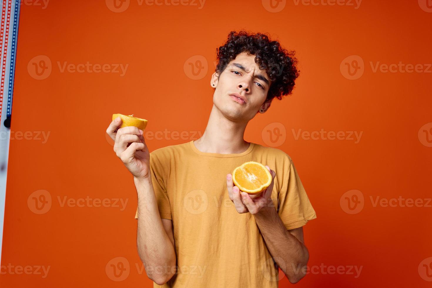 uomo con Riccio capelli arance nel mani studio isolato sfondo foto