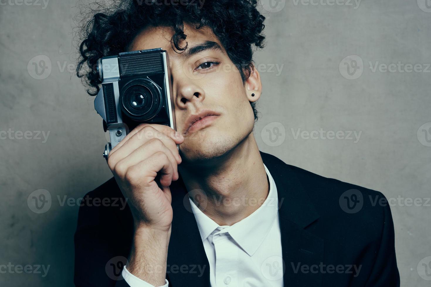 elegante uomo con telecamera nel mano fotografia studio riccioli modello ritratto foto