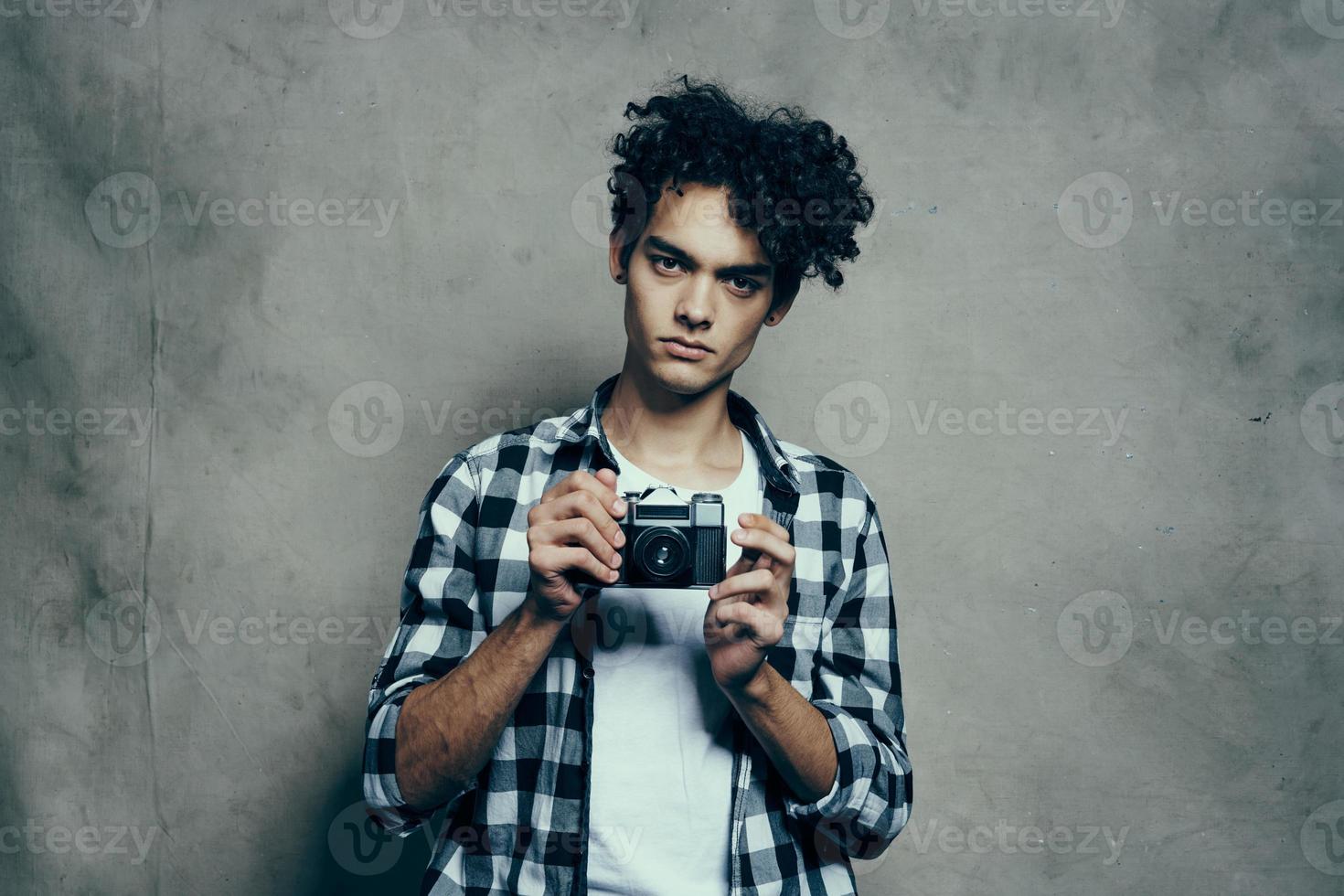 simpatico tipo nel un' plaid camicia e un' maglietta con un' telecamera nel il suo mano modello passatempo studio foto