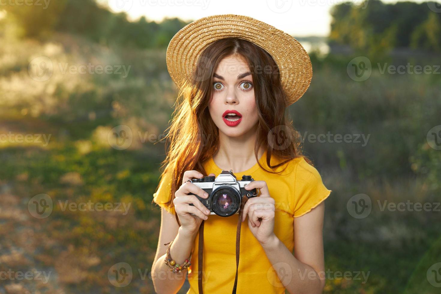 innamorato donna Tenere un' telecamera nel sua mani cappello rosso labbra giallo maglietta fresco aria foto