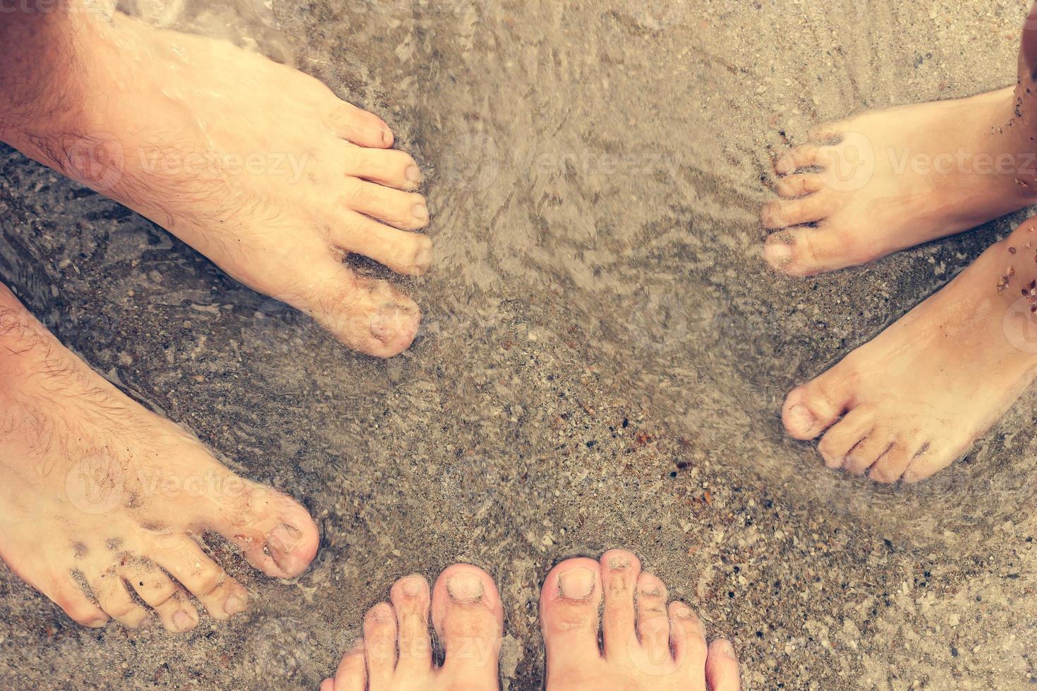 piedi di tre persone in piedi nel il mare. famiglia riposo su il spiaggia e nuoto nel il mare. foto