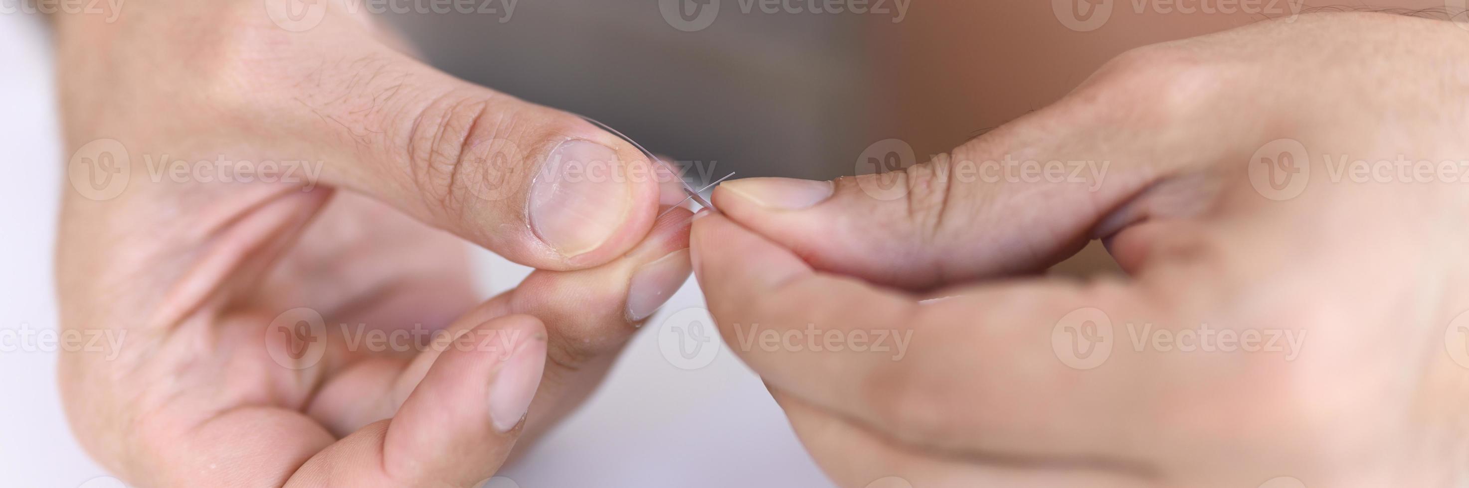 mani dell'uomo che lega una lenza con una mosca su un amo da pesca foto