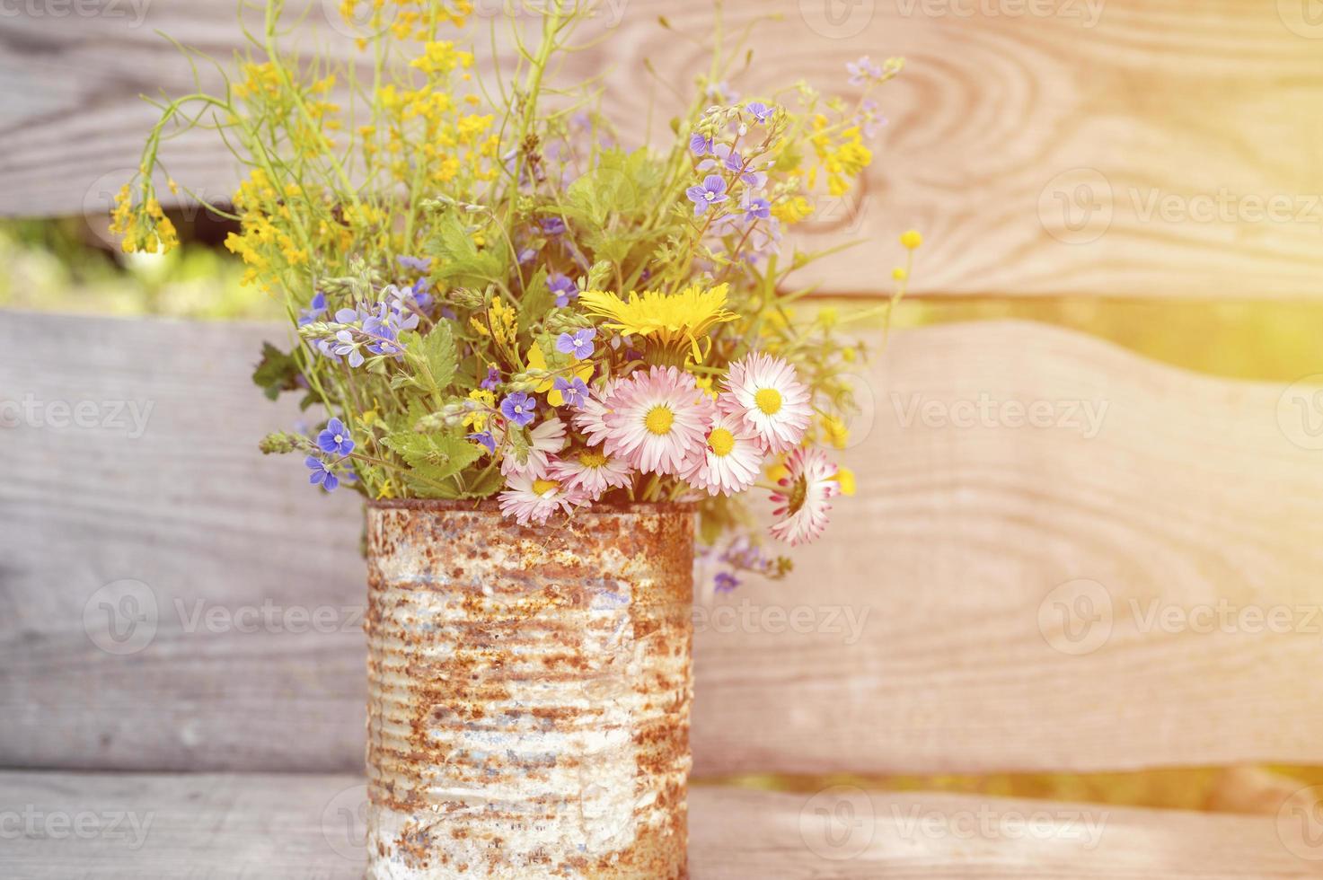 un bouquet di fiori di campo di nontiscordardime, margherite e denti di leone gialli in piena fioritura in un vaso rustico foto