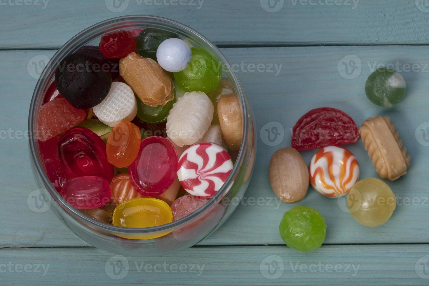 caramelle nel un' vaso su un' blu sfondo. multicolore caramello su un' di legno tavola. dolci. foto