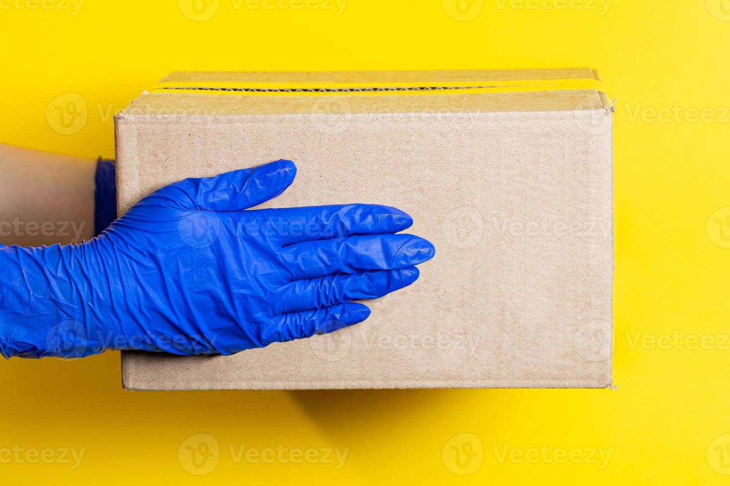 un uomo in guanti di lattice consegna un pacco su sfondo giallo foto