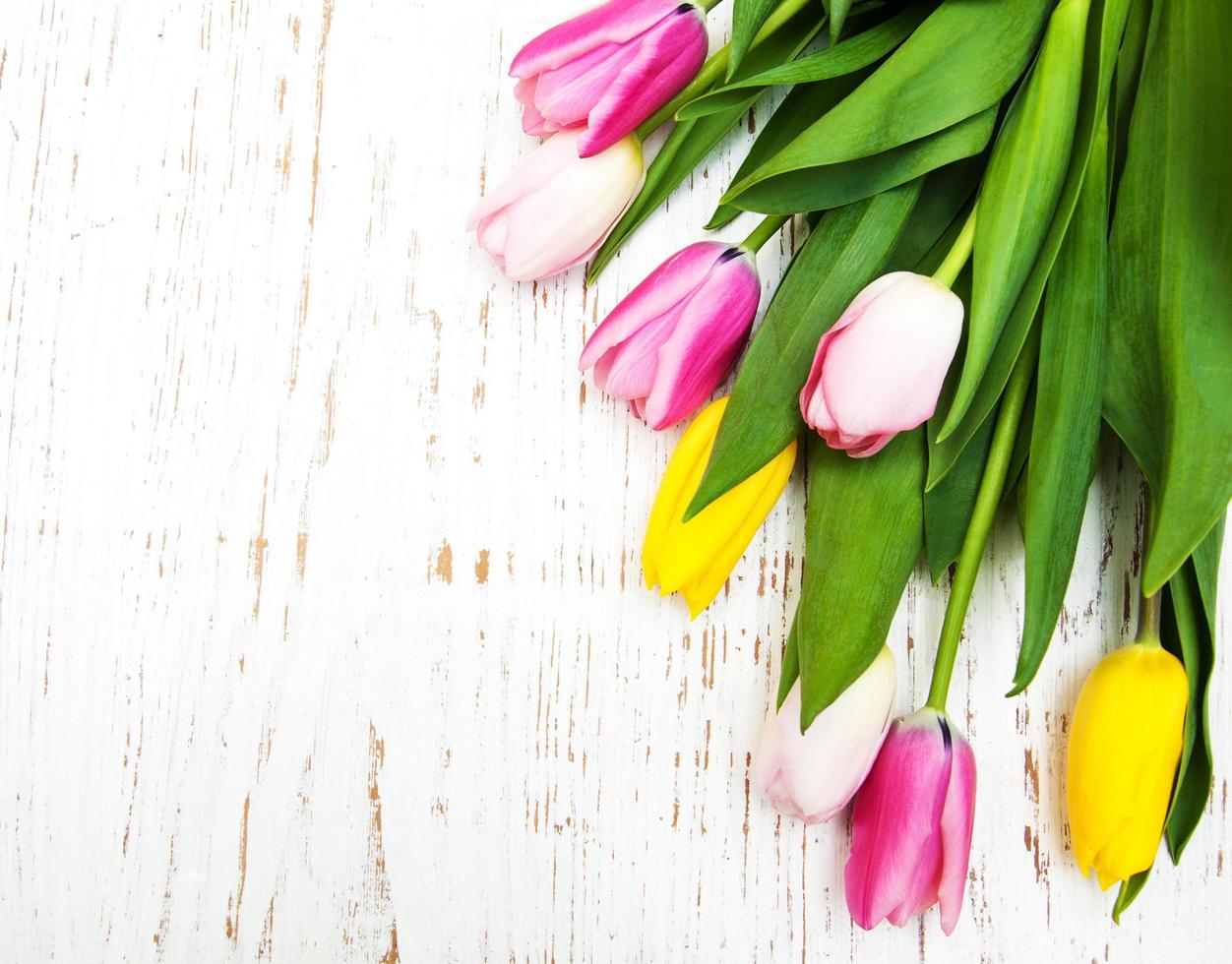 bouquet di tulipani rosa e gialli su uno sfondo di legno foto