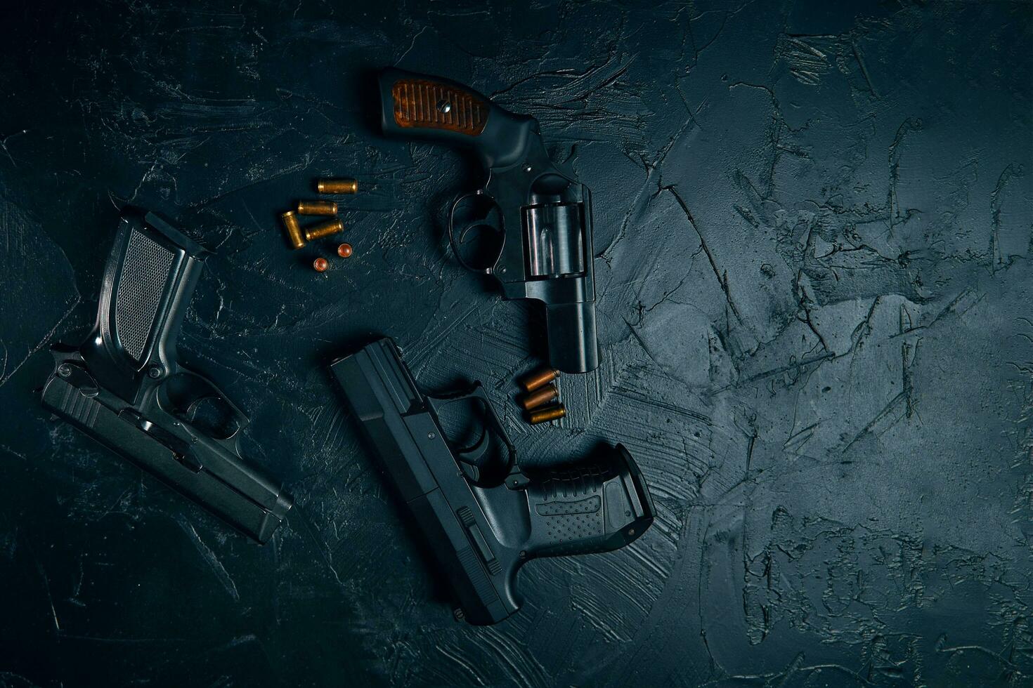 tre pistole e proiettili sulla tavola nera foto