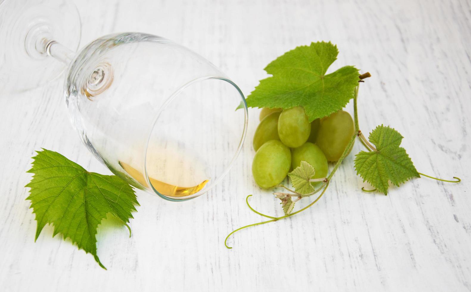 bicchiere di vino sdraiato su uno sfondo di legno foto