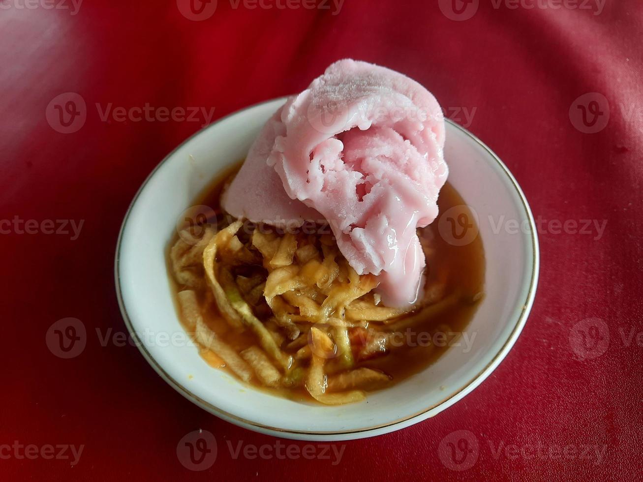 un' rujak o speziato frutta insalata piatto sormontato con fragola ghiaccio crema foto