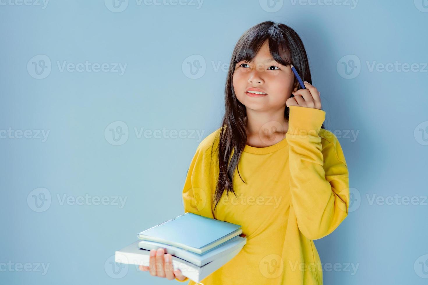 ragazza alunno Tenere mucchio di libri isolato su blu sfondo foto