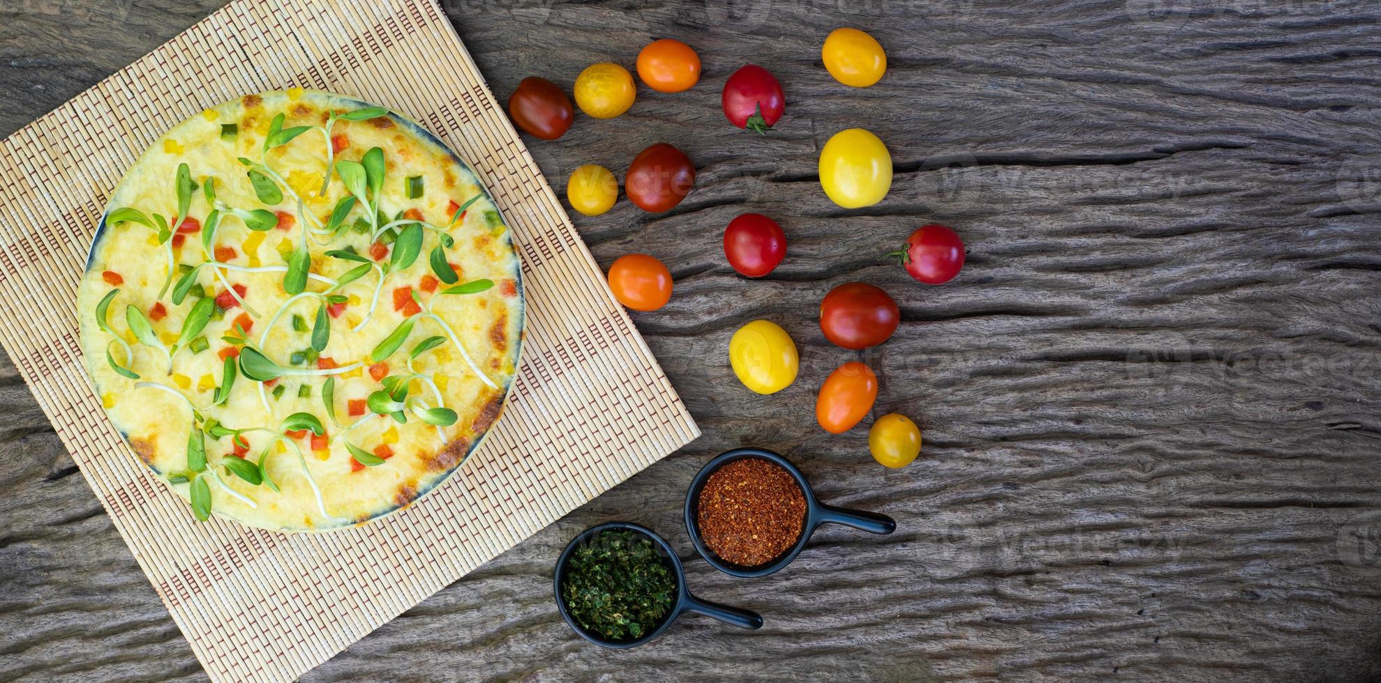 pizza vegetariana fatta in casa con pomodorini su uno sfondo di legno foto