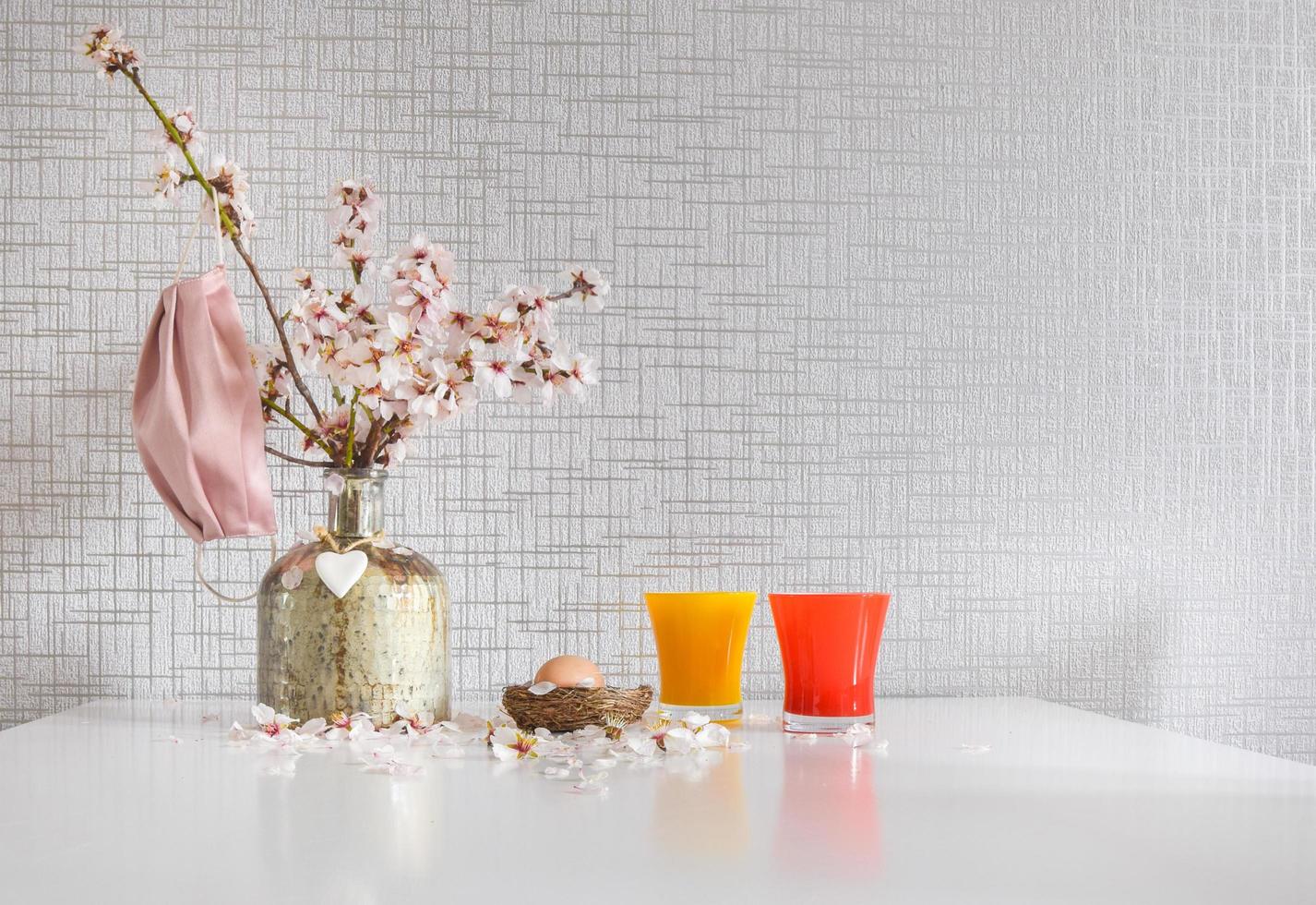 fiori di primavera margherita in vaso con maschera facciale rosa appesa e uovo di Pasqua crudo foto