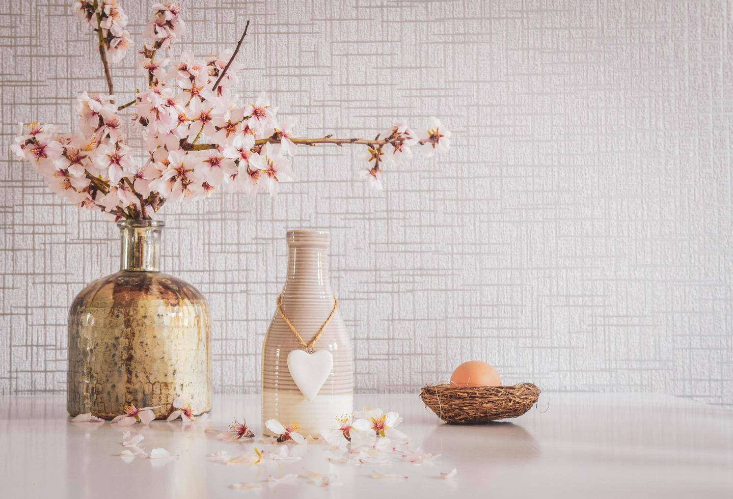 primavera vibrante tavolo bianco allestito con margherite, uovo di Pasqua e un ciondolo a cuore foto