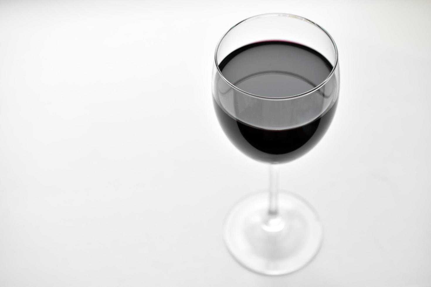 grande bicchiere di vino rosso su sfondo bianco foto