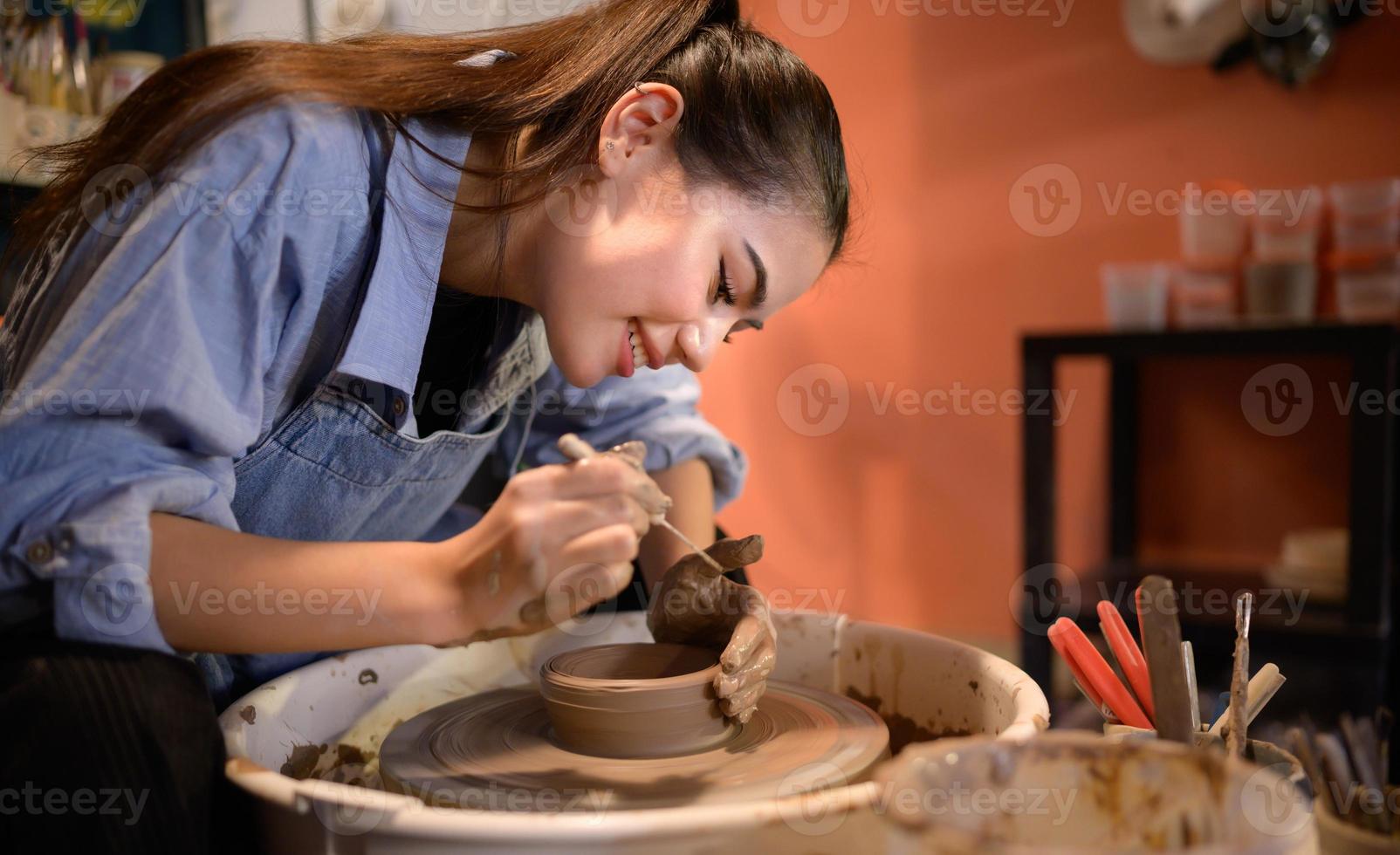 ceramica artista, giovane femmina fabbricazione un' pezzo di argilla modanatura con calma e meticolosamente nel ordine per produrre il maggior parte attraente opera possibile, foto