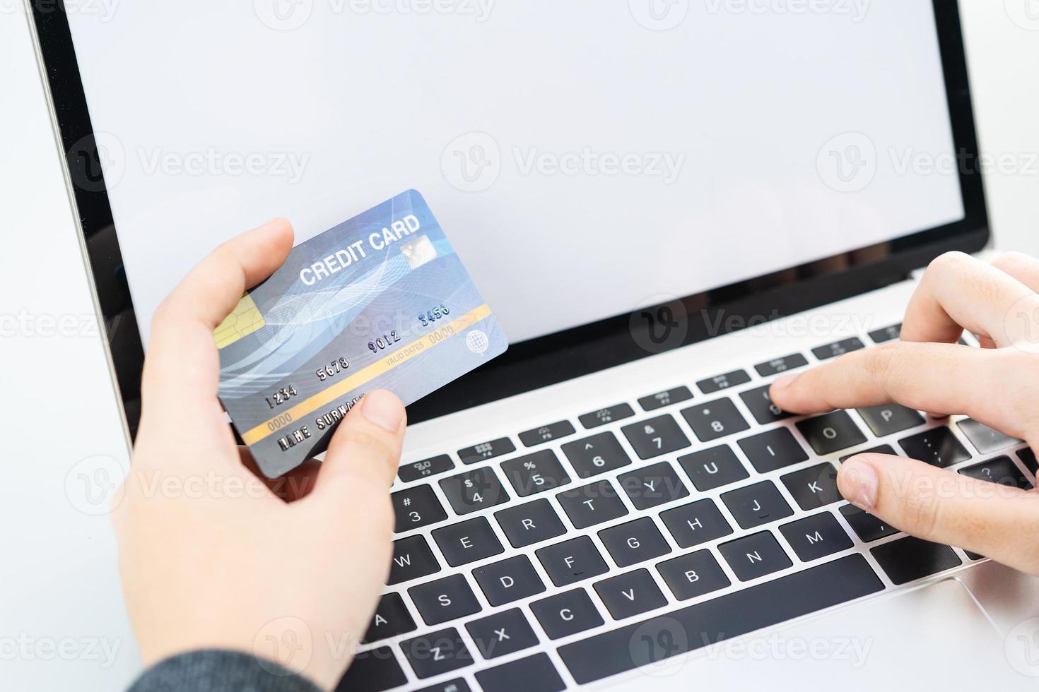 primo piano delle mani femminili che tengono la carta di credito che effettua il pagamento online foto